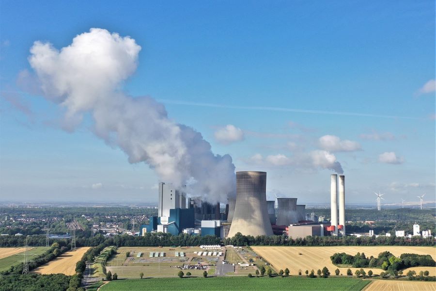 Image of a power plant surrounded by fields and a blue sky